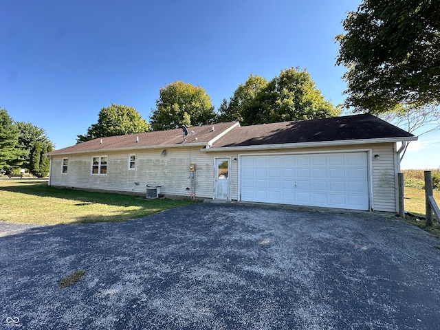 exterior space with a lawn, cooling unit, and a garage