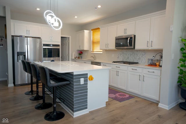 kitchen with white cabinets, light hardwood / wood-style floors, and appliances with stainless steel finishes