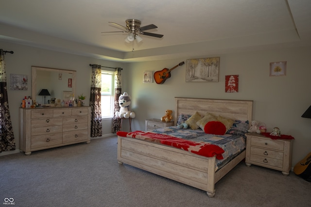 carpeted bedroom featuring a tray ceiling and ceiling fan