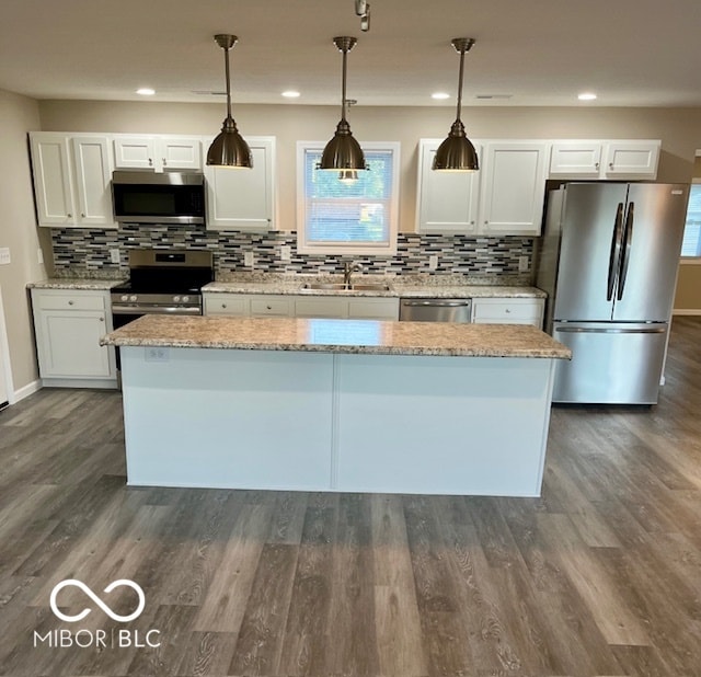 kitchen with dark hardwood / wood-style floors, white cabinetry, appliances with stainless steel finishes, decorative light fixtures, and light stone countertops