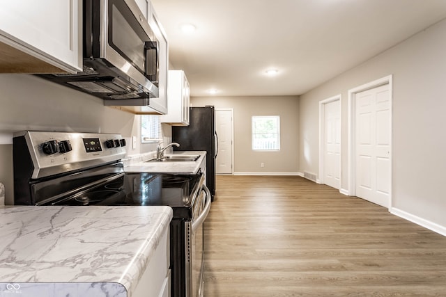 kitchen featuring appliances with stainless steel finishes, sink, light hardwood / wood-style flooring, and white cabinets