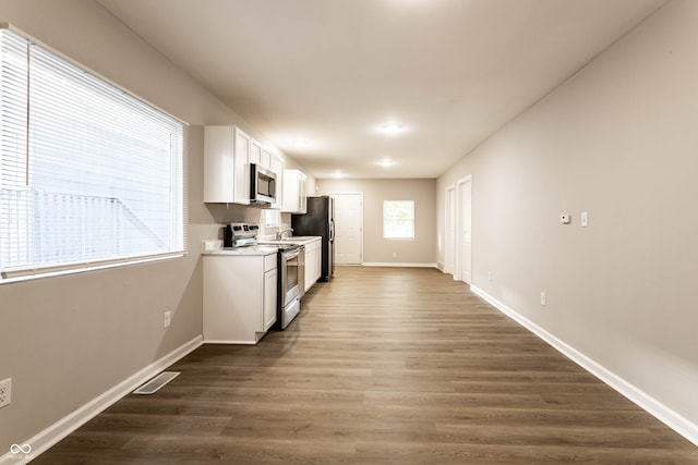 kitchen featuring appliances with stainless steel finishes, dark wood-type flooring, and white cabinets