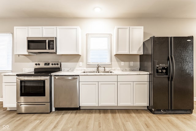 kitchen featuring white cabinets, appliances with stainless steel finishes, light wood-type flooring, and sink