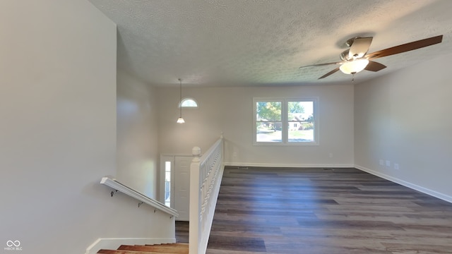 unfurnished living room featuring ceiling fan, a textured ceiling, and dark hardwood / wood-style flooring