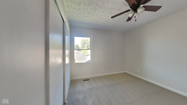 empty room featuring a textured ceiling, carpet, and ceiling fan