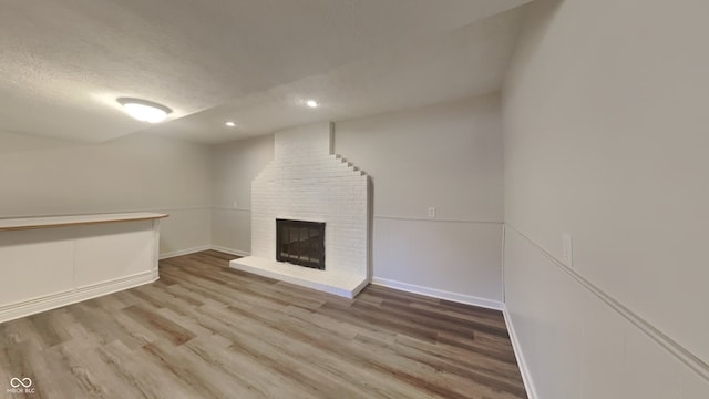 unfurnished living room featuring a textured ceiling, wood-type flooring, and a fireplace