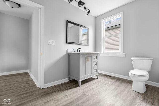 bathroom featuring track lighting, vanity, hardwood / wood-style floors, and toilet