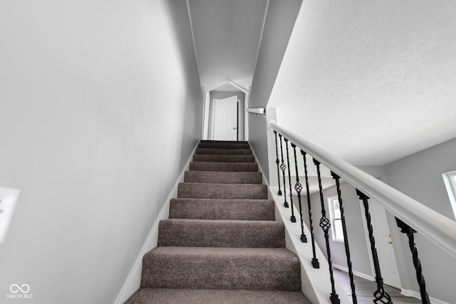 staircase featuring a textured ceiling and wood-type flooring