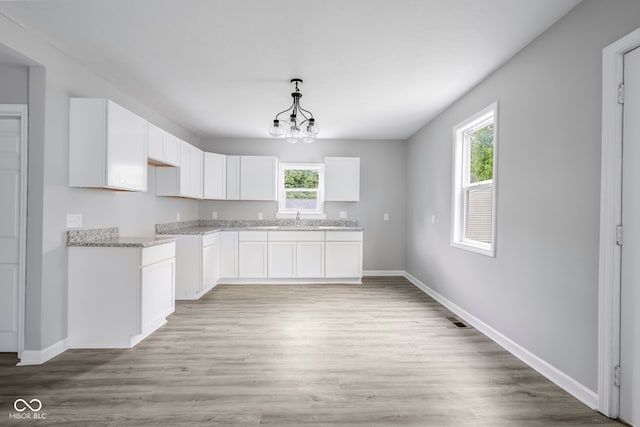 kitchen featuring pendant lighting, white cabinets, light hardwood / wood-style floors, and a healthy amount of sunlight