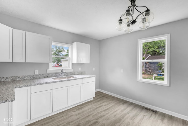 kitchen featuring white cabinets, light hardwood / wood-style flooring, sink, and a healthy amount of sunlight