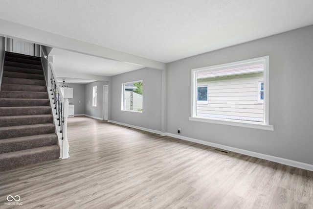 unfurnished living room featuring a textured ceiling and light hardwood / wood-style floors