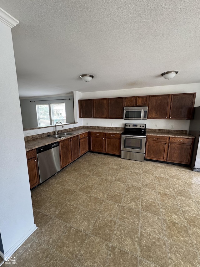 2307 Blackthorn Dr, Franklin, IN 46131 - kitchen with appliances with stainless steel finishes, a sink, a textured ceiling, dark countertops, and dark brown cabinets