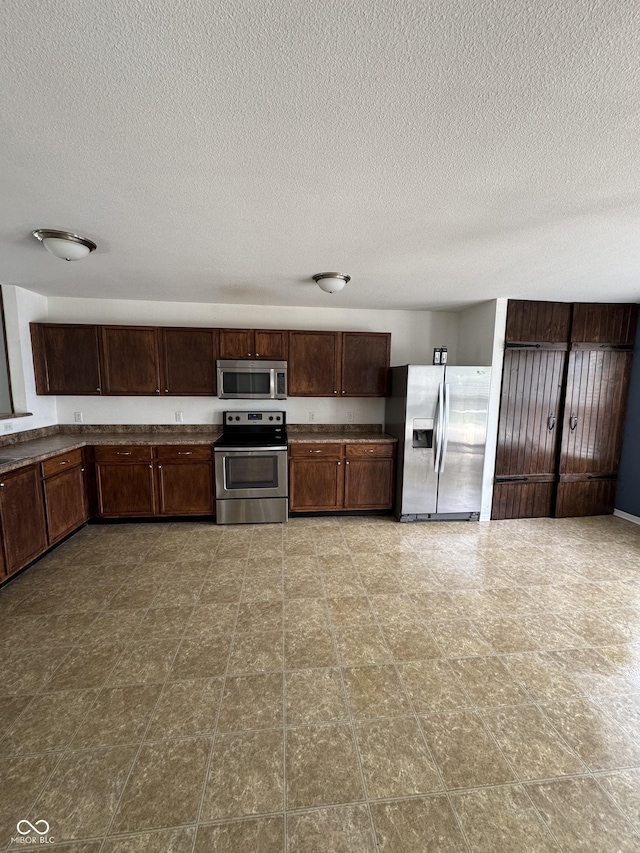 2307 Blackthorn Dr, Franklin, IN 46131 - kitchen with appliances with stainless steel finishes, a textured ceiling, dark brown cabinets, and dark countertops