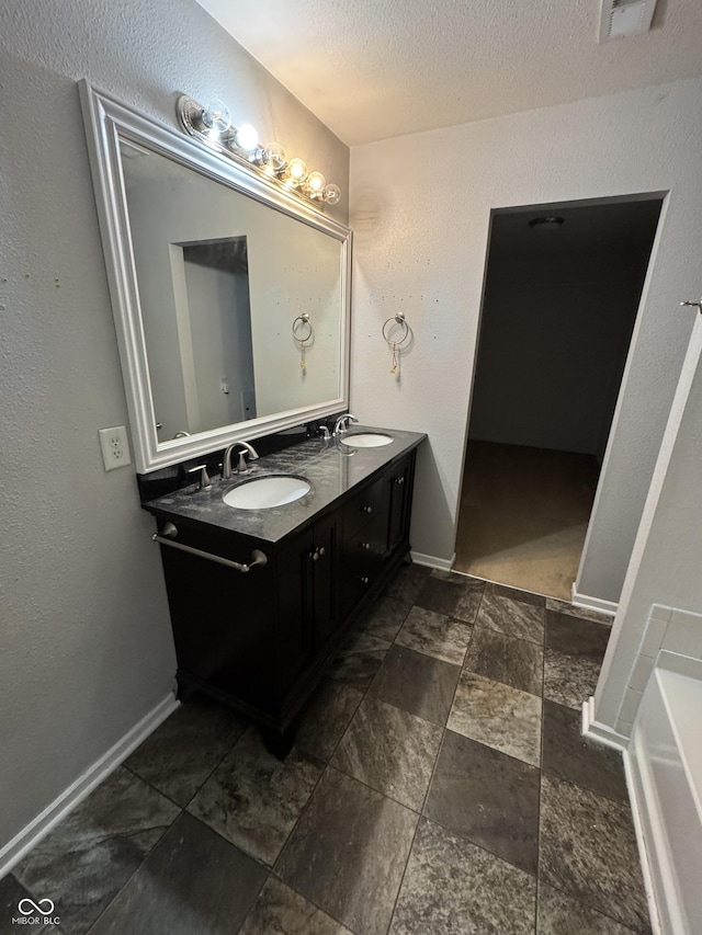 2307 Blackthorn Dr, Franklin, IN 46131 - bathroom featuring double vanity, baseboards, a textured ceiling, and a bathtub