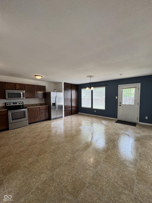 2307 Blackthorn Dr, Franklin, IN 46131 - kitchen with stainless steel appliances, a textured ceiling, a chandelier, baseboards, and dark brown cabinets