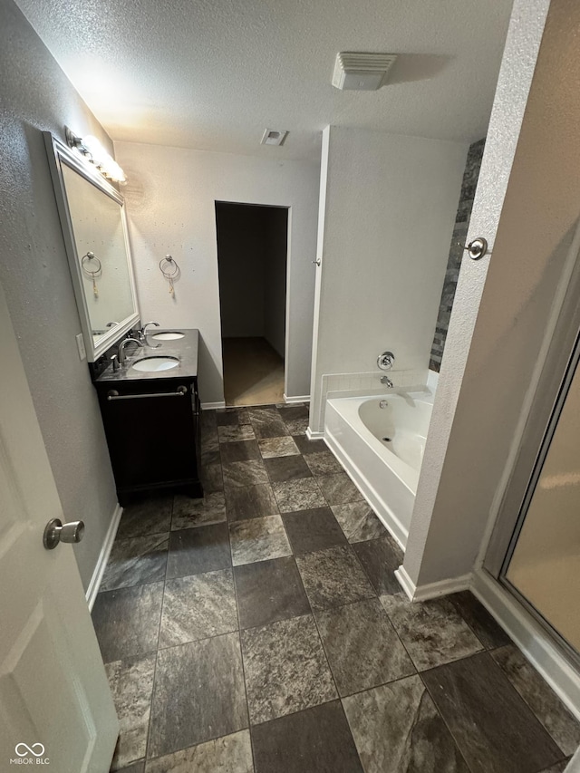 2307 Blackthorn Dr, Franklin, IN 46131 - full bathroom featuring a textured ceiling, a bath, double vanity, a shower stall, and baseboards