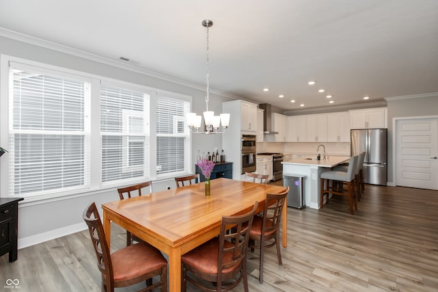 dining area with an inviting chandelier, light hardwood / wood-style floors, sink, and crown molding