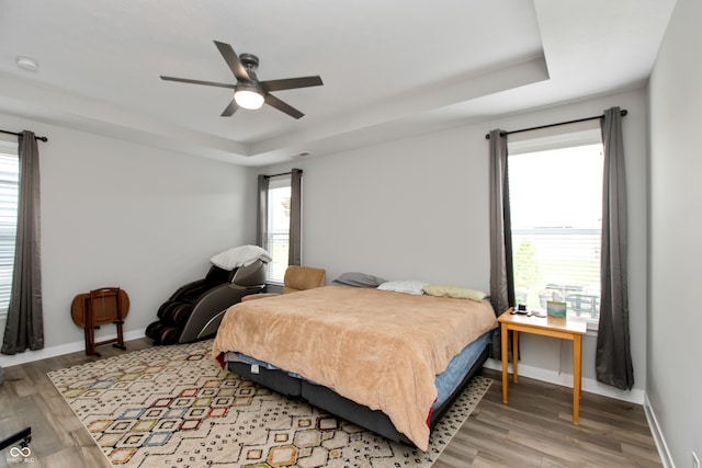 bedroom featuring light wood-type flooring, multiple windows, and ceiling fan