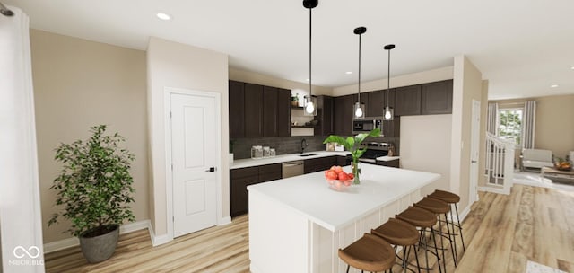 kitchen with stainless steel appliances, a kitchen island, dark brown cabinets, sink, and light hardwood / wood-style floors