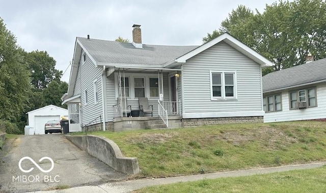 view of front facade with a chimney, a front yard, aphalt driveway, an outbuilding, and a garage