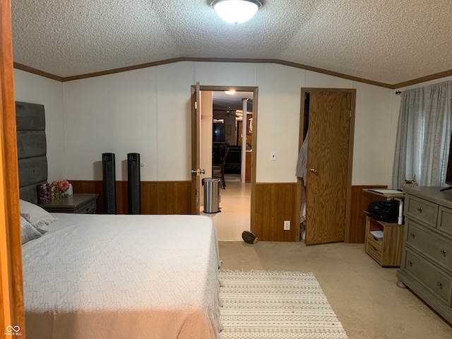 bedroom featuring a textured ceiling, lofted ceiling, wood walls, light carpet, and crown molding