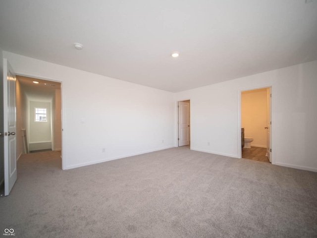 unfurnished bedroom with connected bathroom and light colored carpet