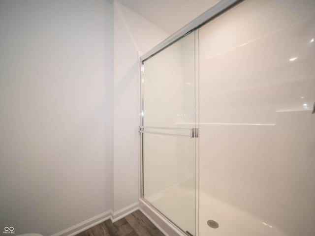 bathroom with a shower with shower door and hardwood / wood-style floors