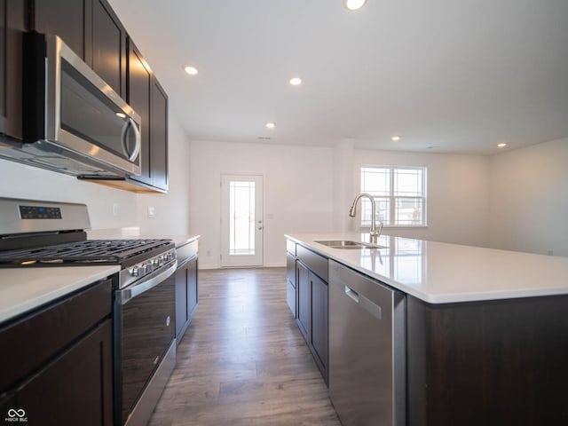 kitchen featuring sink, a center island with sink, light hardwood / wood-style floors, and appliances with stainless steel finishes