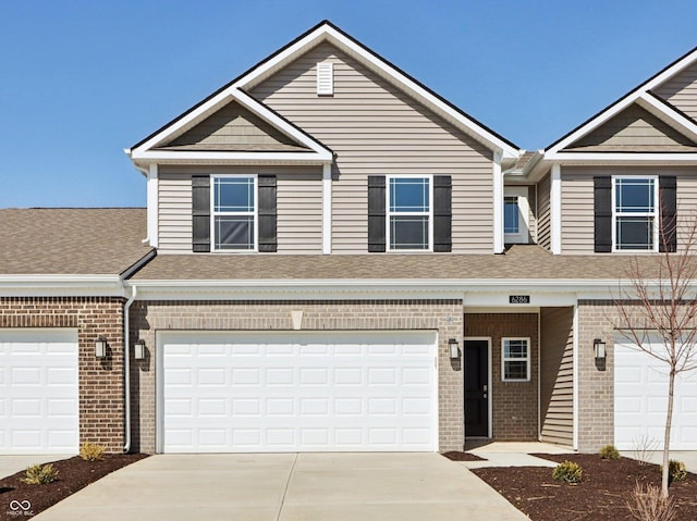 townhome / multi-family property with brick siding, an attached garage, driveway, and a shingled roof