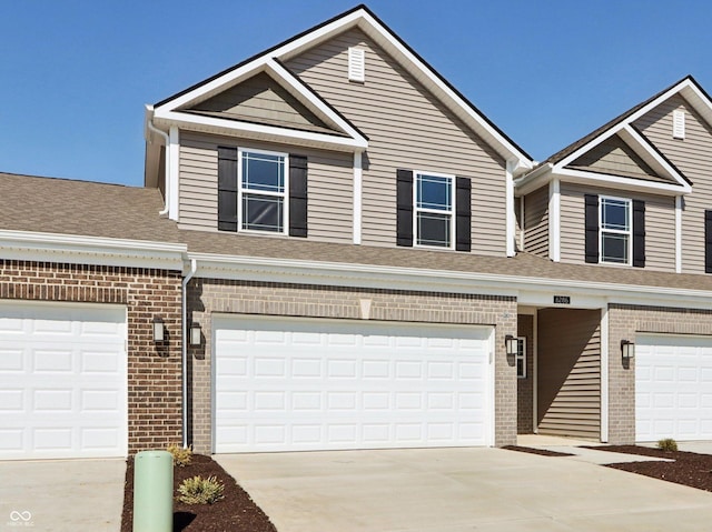 view of property featuring a garage, brick siding, roof with shingles, and driveway