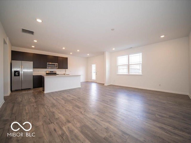 unfurnished living room featuring baseboards, dark wood-type flooring, visible vents, and recessed lighting