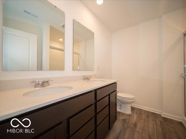 bathroom with double vanity, wood finished floors, a sink, and visible vents