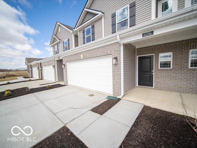 exterior space with driveway, a garage, and brick siding