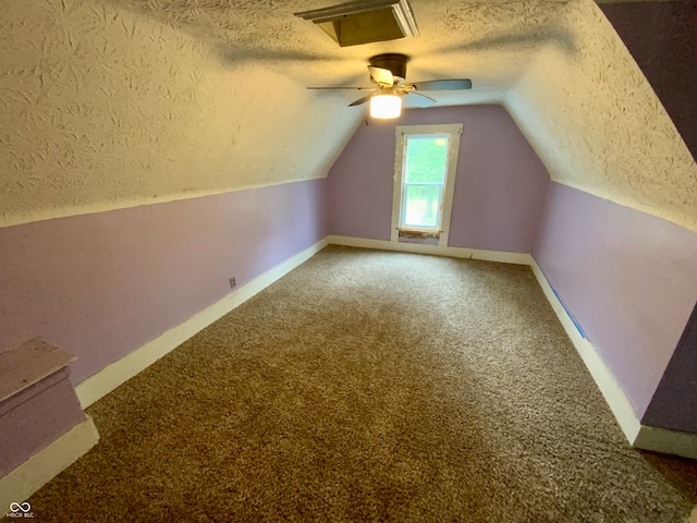 additional living space featuring vaulted ceiling, a textured ceiling, carpet floors, and ceiling fan