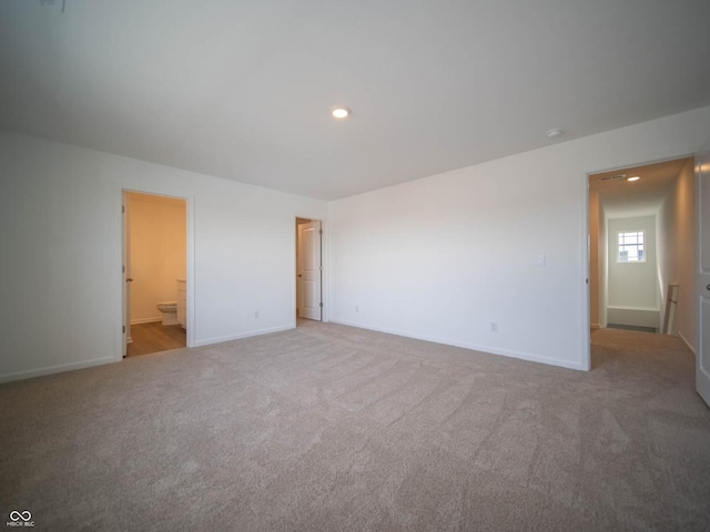 unfurnished bedroom featuring ensuite bathroom and light carpet