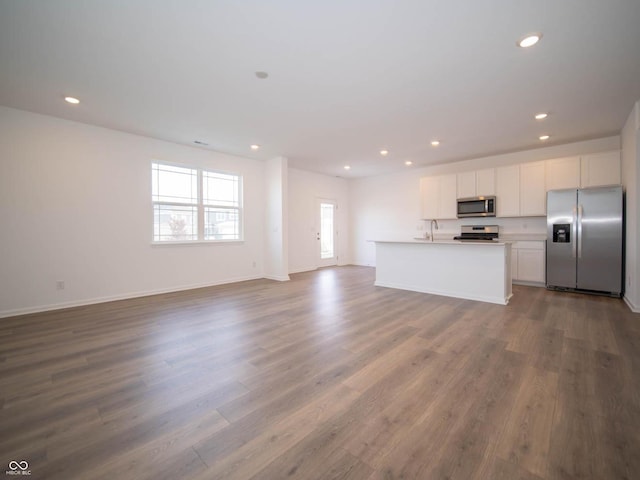 kitchen featuring appliances with stainless steel finishes, sink, hardwood / wood-style flooring, white cabinetry, and a kitchen island with sink