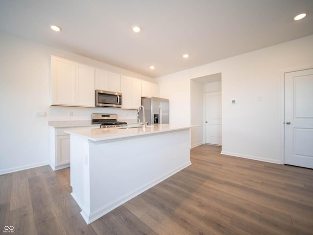 kitchen featuring an island with sink, white cabinets, hardwood / wood-style floors, and appliances with stainless steel finishes