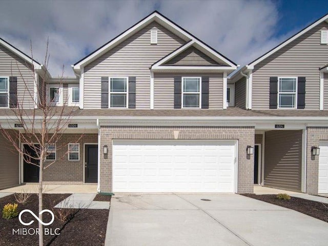 townhome / multi-family property with a garage, concrete driveway, and brick siding