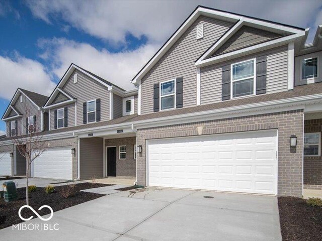 view of property featuring an attached garage, concrete driveway, and brick siding