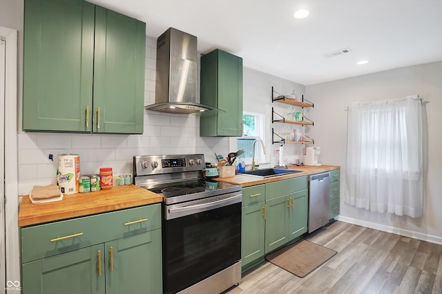 kitchen featuring light wood-type flooring, sink, wall chimney exhaust hood, stainless steel appliances, and green cabinets