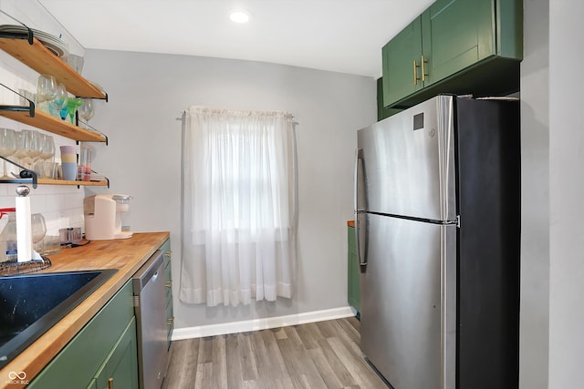 kitchen featuring light hardwood / wood-style flooring, backsplash, appliances with stainless steel finishes, green cabinets, and wood counters