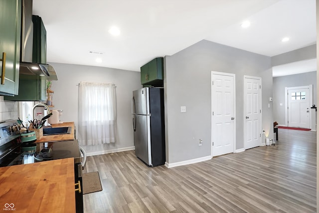 kitchen with light wood-type flooring, sink, stainless steel appliances, green cabinets, and extractor fan