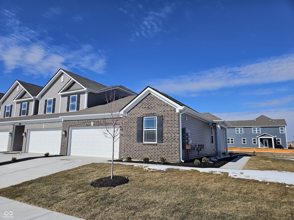 view of front of house with driveway, brick siding, and a front yard