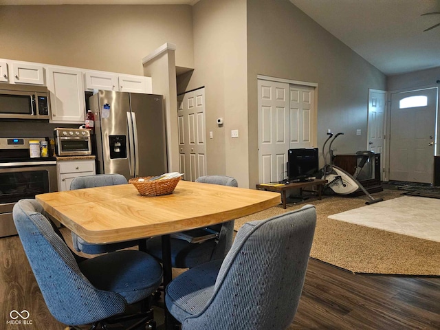 dining space featuring a toaster, high vaulted ceiling, and dark wood-style floors