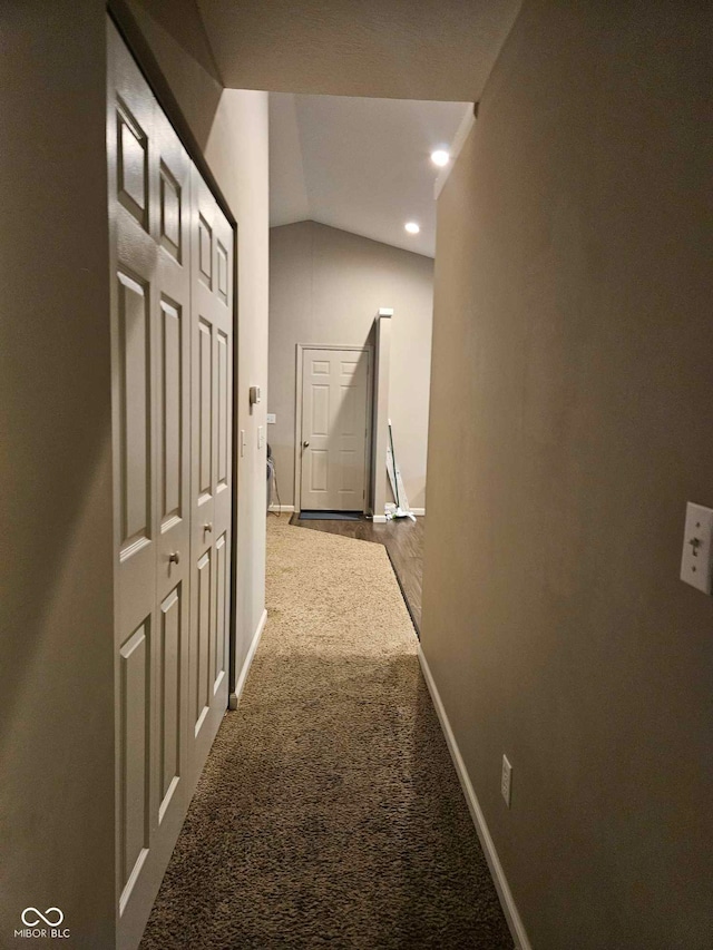 corridor featuring dark colored carpet, recessed lighting, baseboards, and lofted ceiling