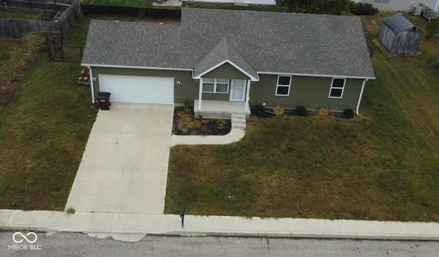 ranch-style home featuring fence, roof with shingles, an attached garage, a front yard, and driveway