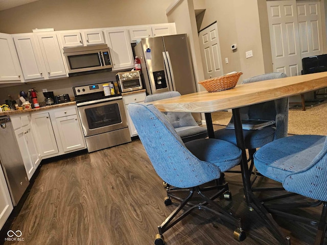 kitchen with light countertops, stainless steel appliances, white cabinetry, a toaster, and dark wood-type flooring