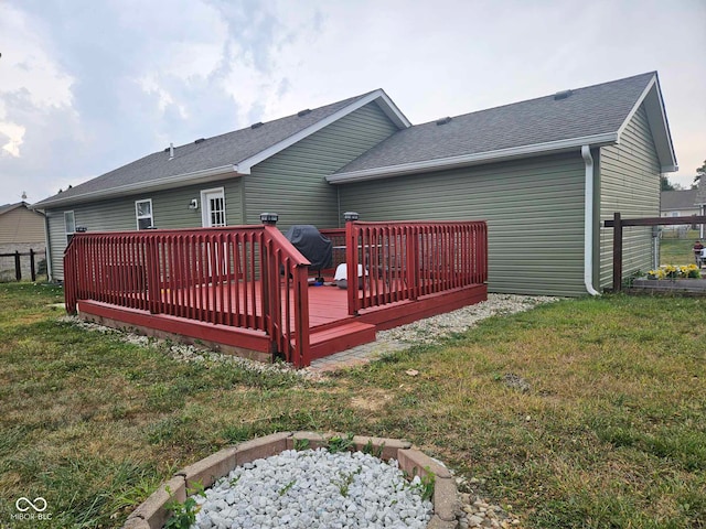 rear view of house featuring a lawn, a deck, fence, and roof with shingles