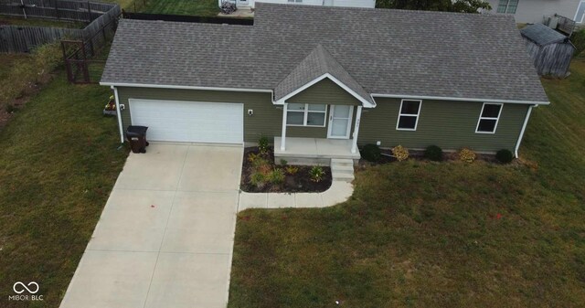 view of front of home with roof with shingles, fence, an attached garage, a front lawn, and concrete driveway