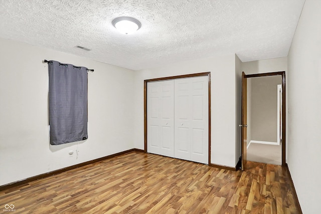 2747 E Midland Rd, Indianapolis, IN 46227 - unfurnished bedroom with light wood-type flooring, a textured ceiling, a closet, and baseboards